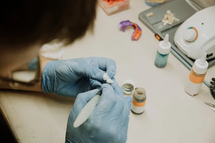 Dental laboratory technician hand-crafting a precision ceramic restoration at Taki Dent — in-house lab quality control ensures every crown and veneer meets the highest standards